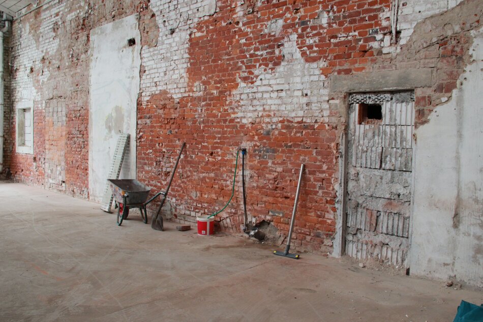 unverputzte Wand mit Ziegelsteinen in einer Halle, Arbeitsgeräte